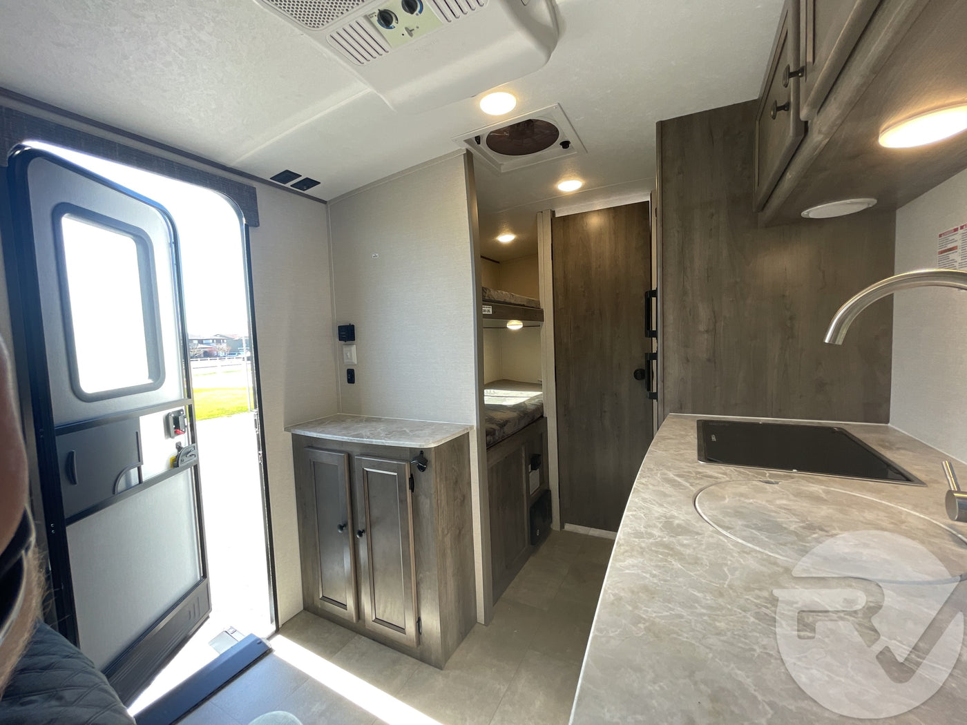 Bright and functional RV rental interior showing the kitchen, entrance, and bunk area with modern finishes. — photo 10
