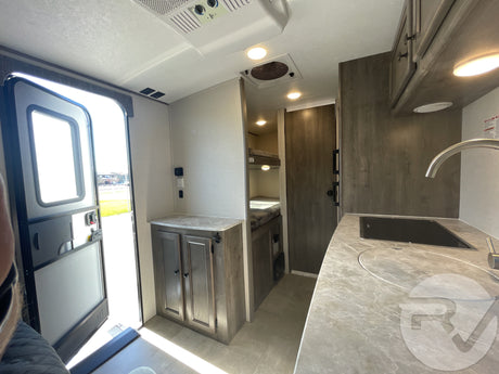 Bright and functional RV rental interior showing the kitchen, entrance, and bunk area with modern finishes.