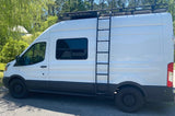 Side view of a white converted van, featuring a roof rack, ladder, and all-terrain tires. Your ultimate rv rental.