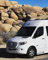 White Mercedes Sprinter RV rental parked in desert landscape with large boulders. Perfect for adventure travel.