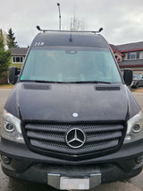 Front view of a black Mercedes-Benz Sprinter van, popular for rv rental, showing roof equipment and obscured plate.