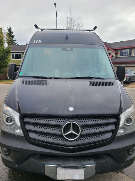 Front view of a black Mercedes-Benz Sprinter van, popular for rv rental, showing roof equipment and obscured plate.