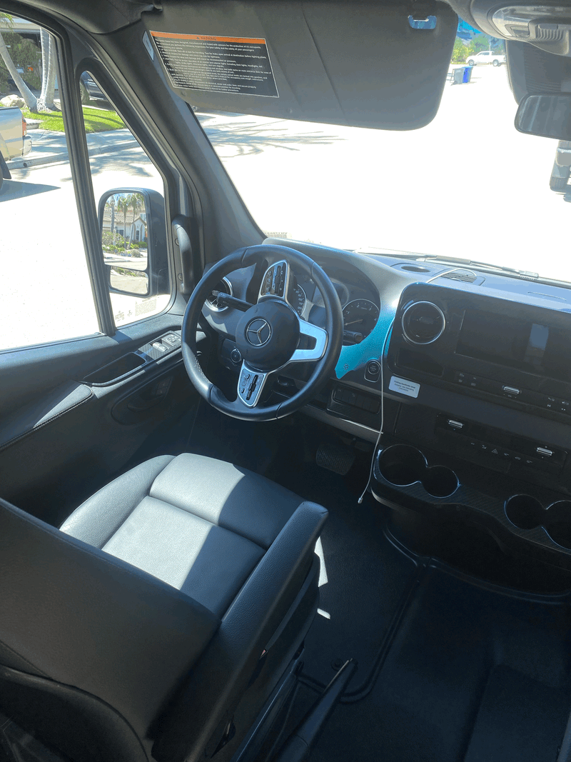 RV rental: Driver's cabin of a Mercedes-Benz motorhome, showing the steering wheel, dashboard, and sun visor warning. — photo 13