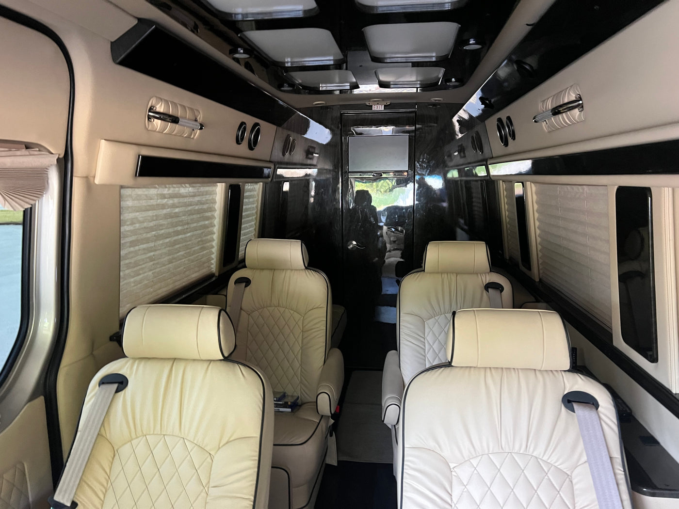 Luxury RV rental interior with cream quilted leather seating, window blinds, and overhead lighting for comfortable travel. — photo 18