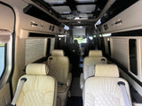 Luxury RV rental interior with cream quilted leather seating, window blinds, and overhead lighting for comfortable travel.