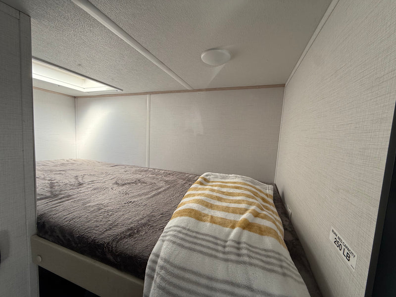 RV rental interior featuring a cozy bunk bed with soft blankets and a 250 LB capacity. — photo 10