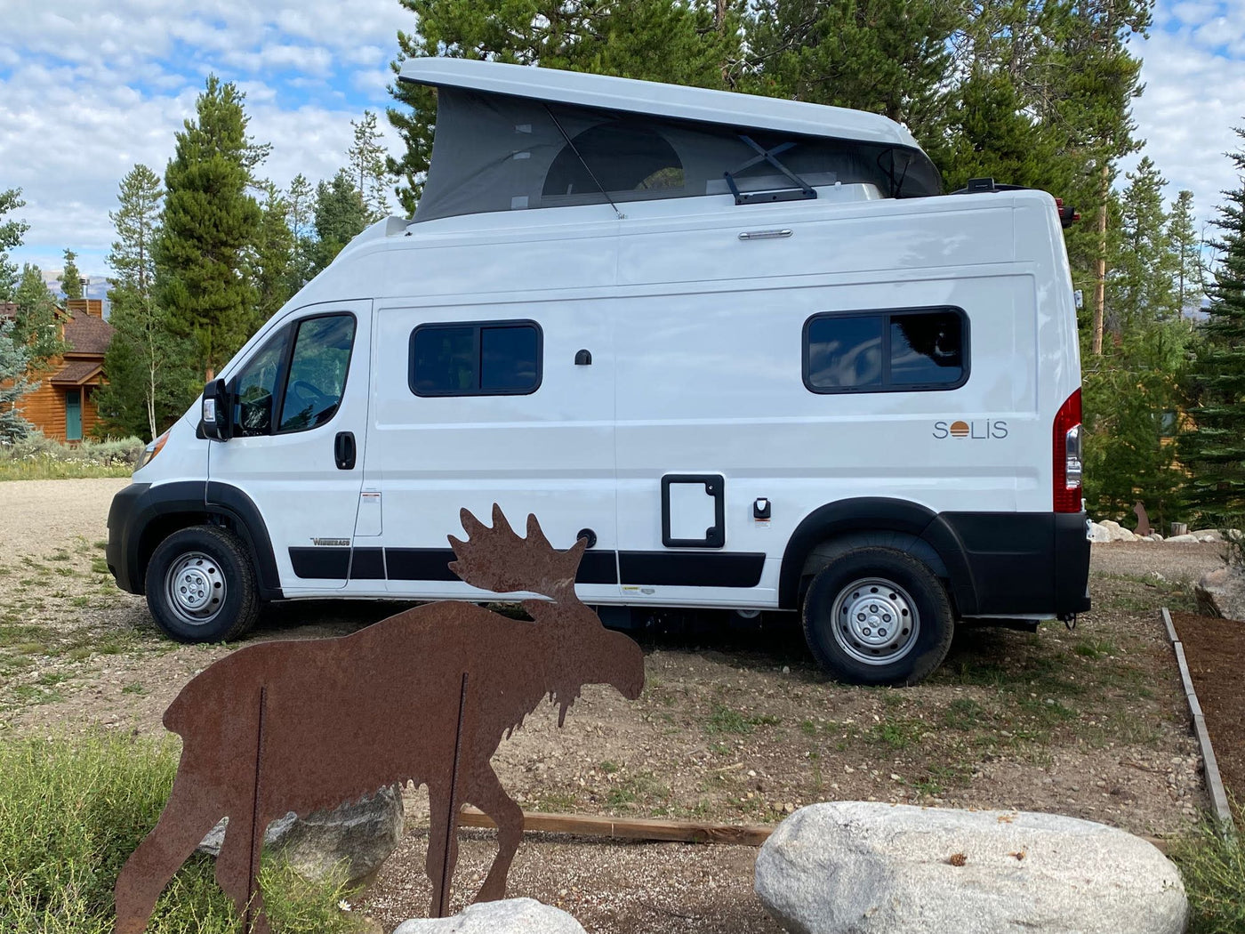  surrounded by trees and mountains.|White Winnebago Solis camper van — photo 2