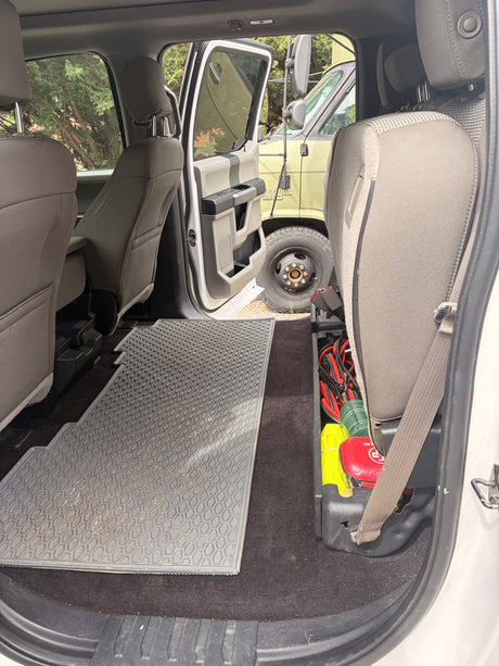 RV rental: Back seat storage with road trip essentials (jumper cables, first aid kit). Durable floor mat & view outside.