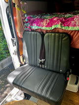 RV rental interior: black seats with belts, colorful bed, and charming decor. Ideal for van life travels.
