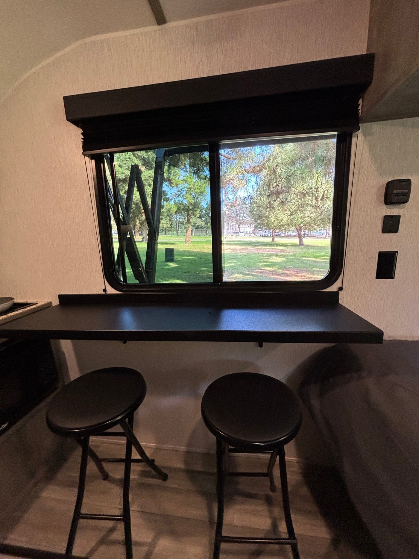 Enjoy the view from this RV rental's cozy window desk with two bar stools, overlooking a serene park. — photo 10