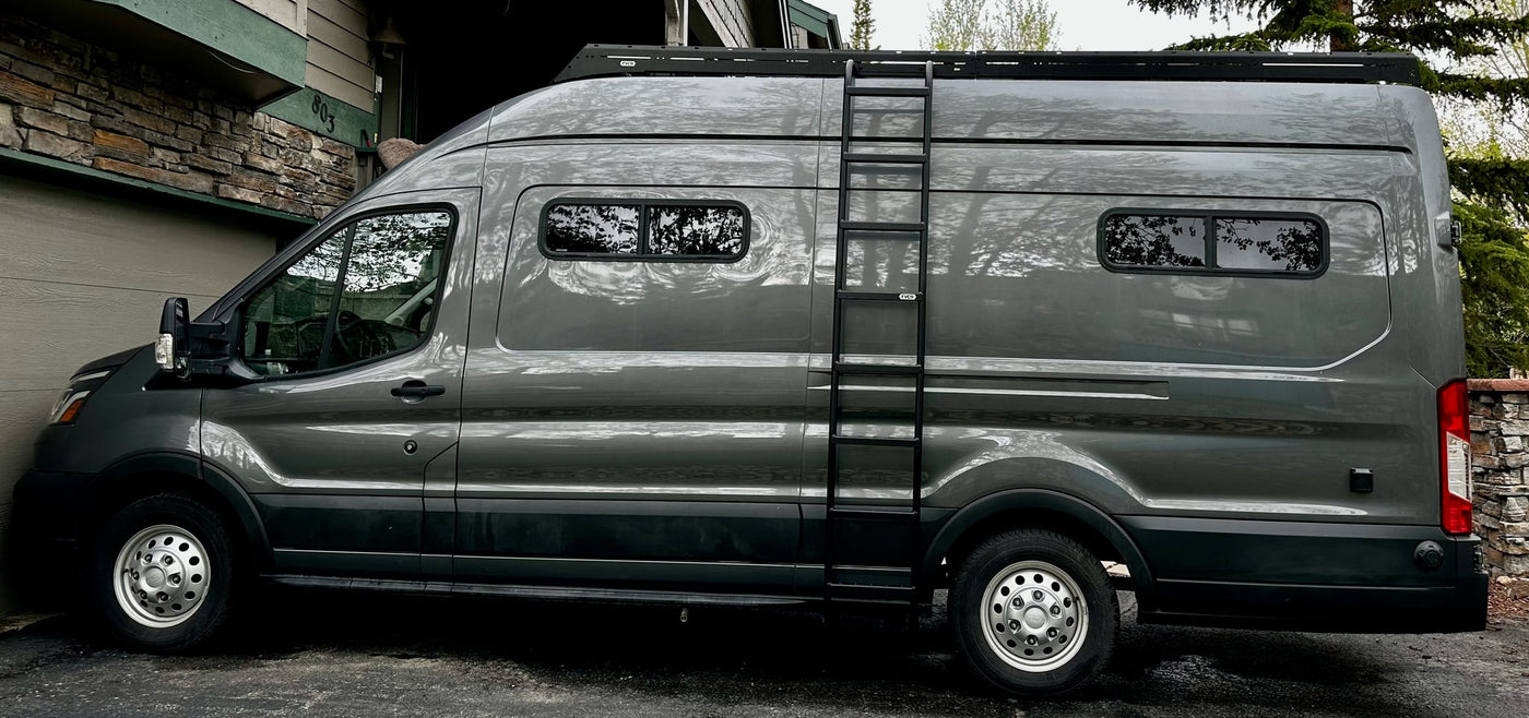  parked in vibrant green grass under a cloudy sky. Perfect for touring.|A large gray camper van — photo 2