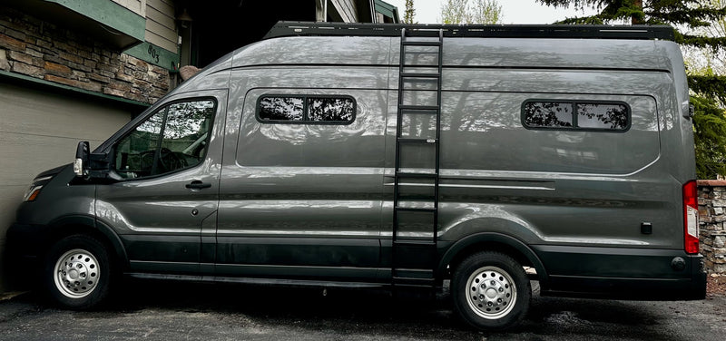  parked in vibrant green grass under a cloudy sky. Perfect for touring.|A large gray camper van — photo 2