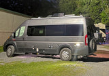 Night shot of a grey camper van, possibly an RV rental, at a campsite with another RV in background. Perfect for road trips.