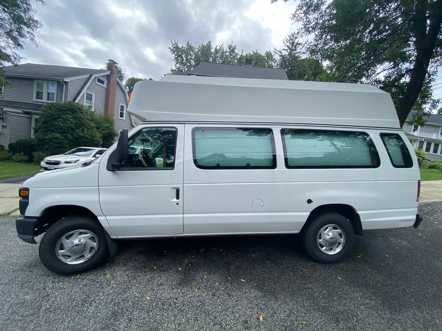 White high-top van, ideal for an RV rental or camper conversion, parked on a residential street.