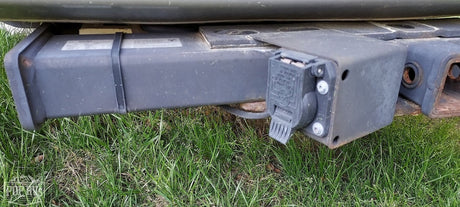 Close-up of an RV rental's robust hitch receiver and attached multi-pin trailer wiring for towing.