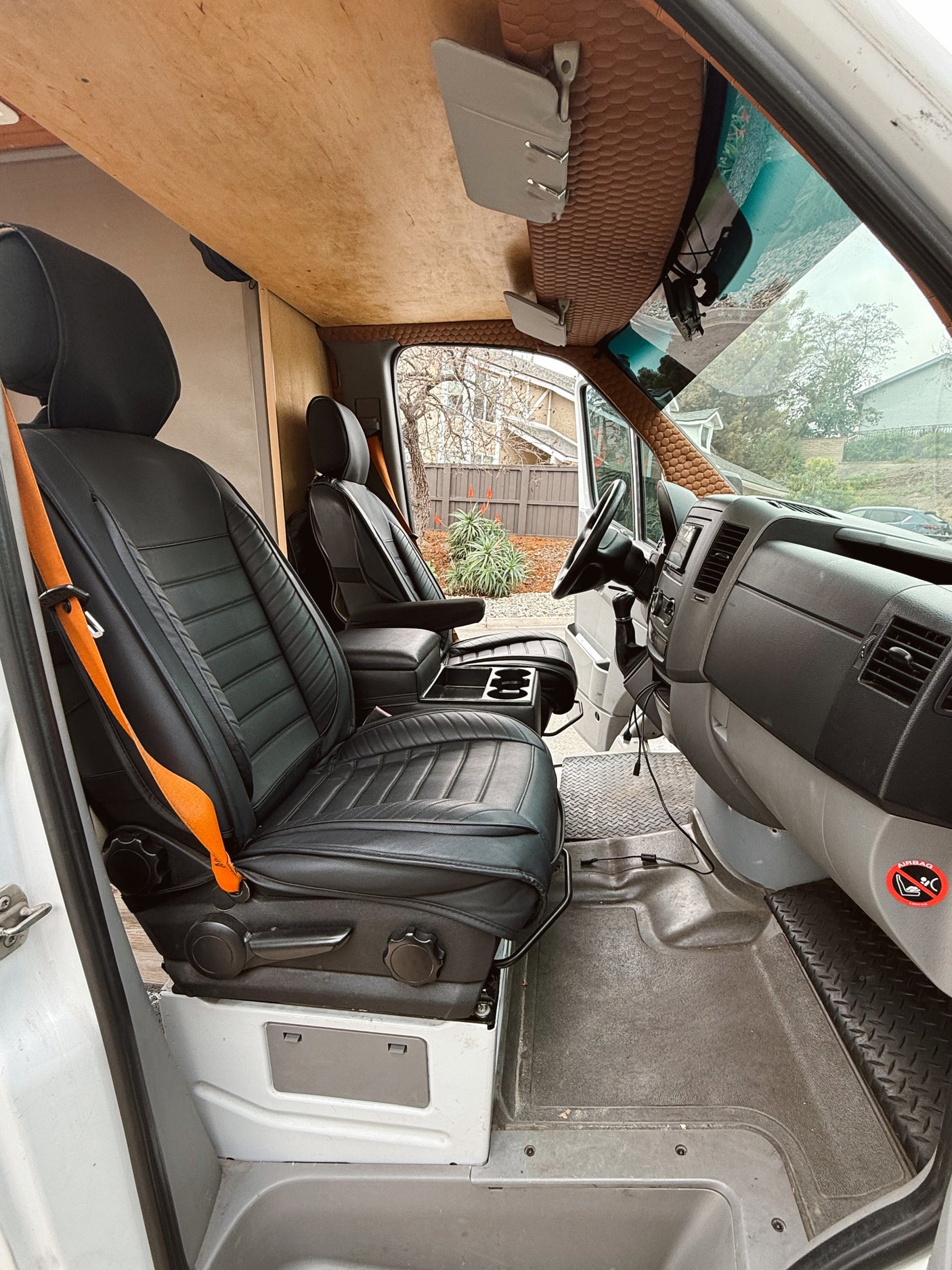 Inside an RV rental: black seats, custom wooden ceiling, and textured brown headliner in the driver's cabin.