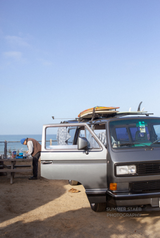 RV rental adventure: VW van, surfboards, and beachside cooking with ocean views.