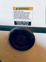RV rental fresh water connection with warning label: "Potable water only." Sanitize & drain tank for safety.
