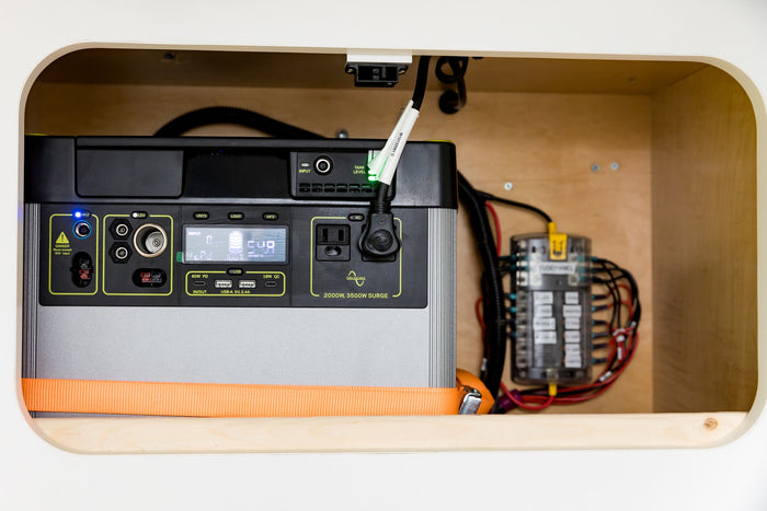 This RV rental's off-grid power setup: a secured portable power station and fuse panel inside a custom compartment.