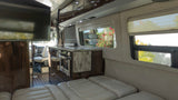 Inside this luxury rv rental, discover a spacious living area with a TV, fully-equipped kitchen, and comfortable bed.