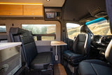 An inviting RV rental interior showing passenger seats, a removable table, and a touchscreen control panel for comfortable travel.