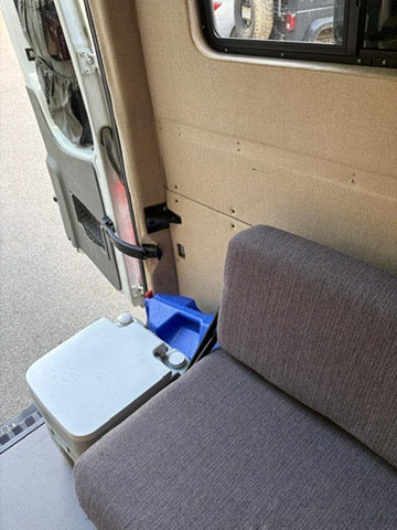 Inside an rv rental: a cozy seat, portable toilet, and water jug. Essential amenities for your road trip comfort.