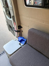 Inside an rv rental: a cozy seat, portable toilet, and water jug. Essential amenities for your road trip comfort.