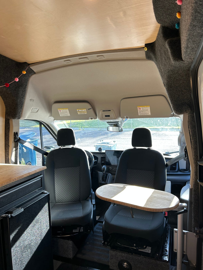 Interior of an RV rental showing the front cab with swivel seats, a compact table, and wooden cabinetry. — photo 5