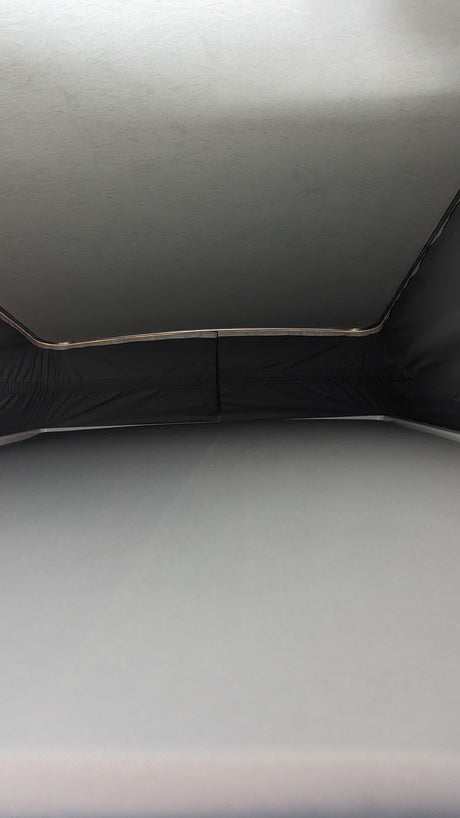 RV rental pop-top view: Raised ceiling, dark fabric walls, and mattress inside a campervan for comfortable travel.