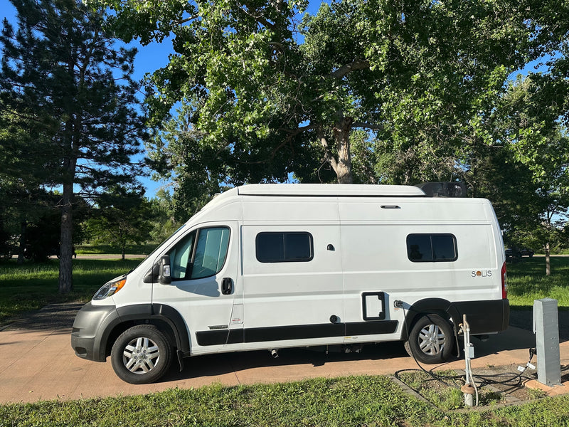 White Winnebago Solis rv rental van parked at a sunny campsite with utility hookups. — photo 3