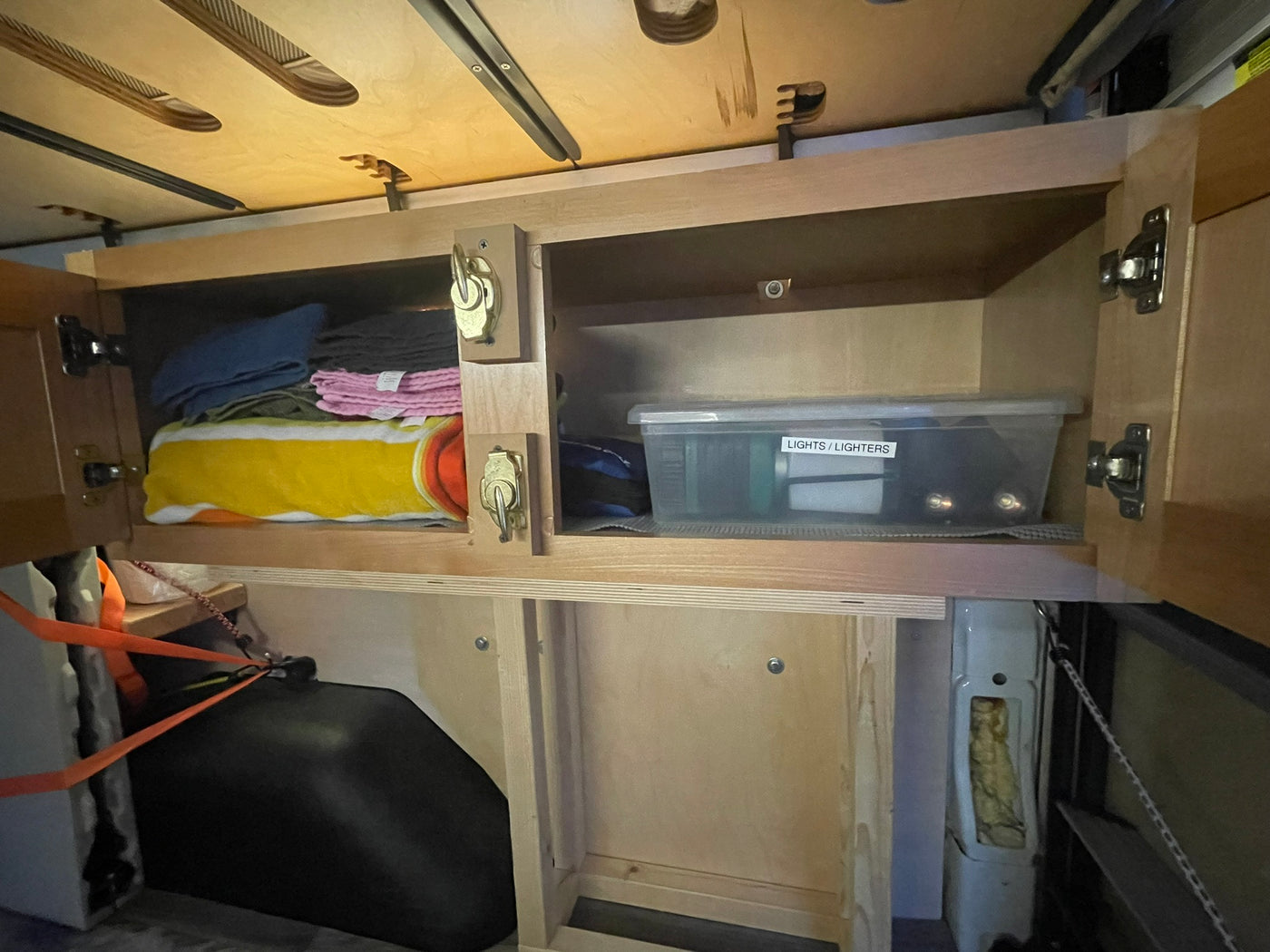 Organized RV rental interior: Custom wooden cabinets and shelves offer practical storage for items like towels and lights. — photo 14