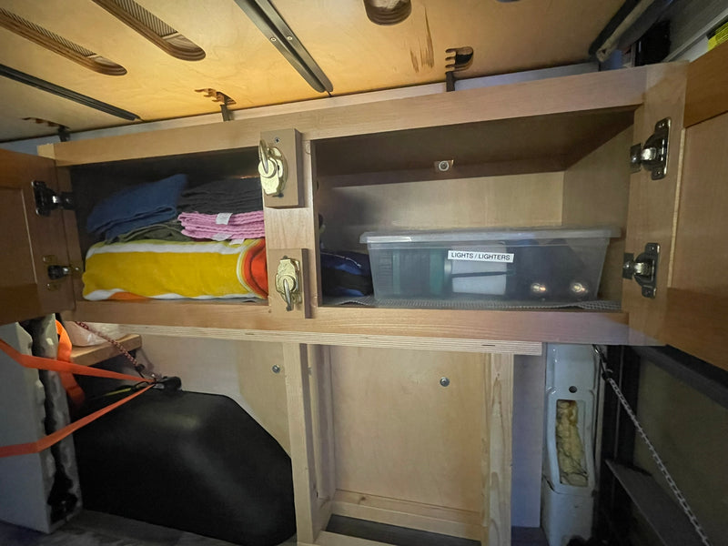 Organized RV rental interior: Custom wooden cabinets and shelves offer practical storage for items like towels and lights. — photo 14