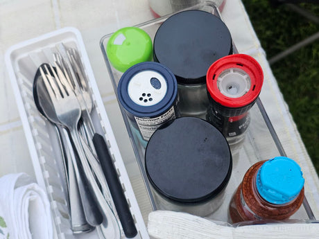 RV rental camp kitchen: Organized silverware, spices, and a pepper grinder ready for outdoor meals.