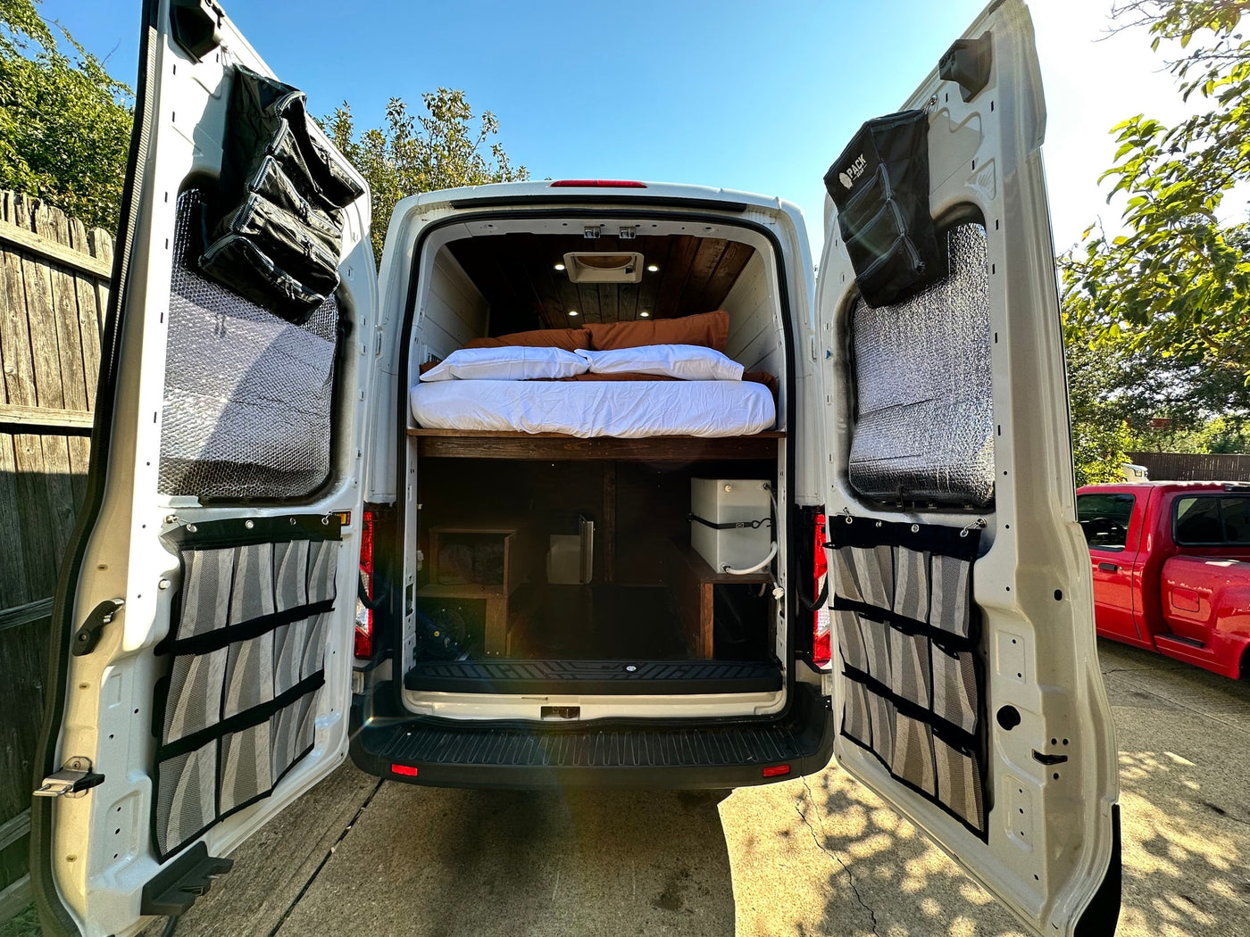  and a comfortable bed in a custom van.|White RV rental van camping setup on gravel: chairs — photo 9