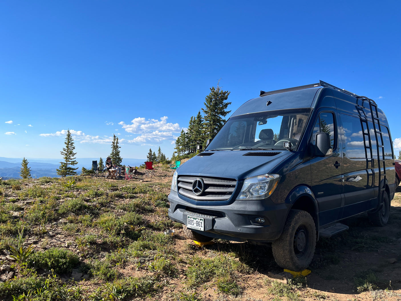 Ultimate RV rental adventure! Blue camper van parked on a mountain overlooking scenic vistas for off-grid camping.