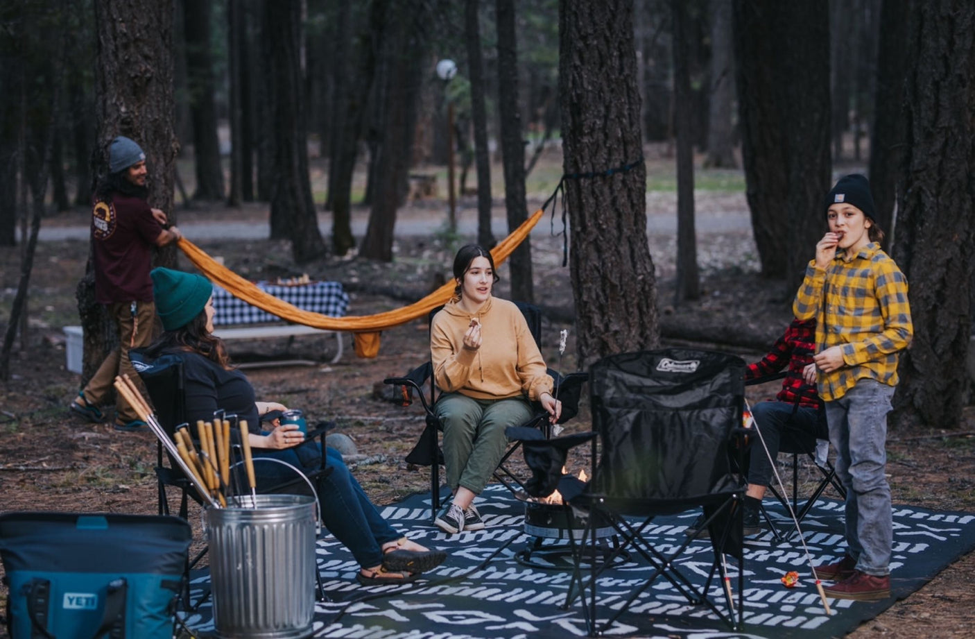 Friends enjoying a cozy campfire and s'mores in the forest, perfect after an RV rental adventure.