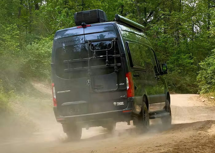 A Thor "Tranquility" Mercedes Sprinter RV rental kicks up dust on a forest trail, ready for off-road adventures.