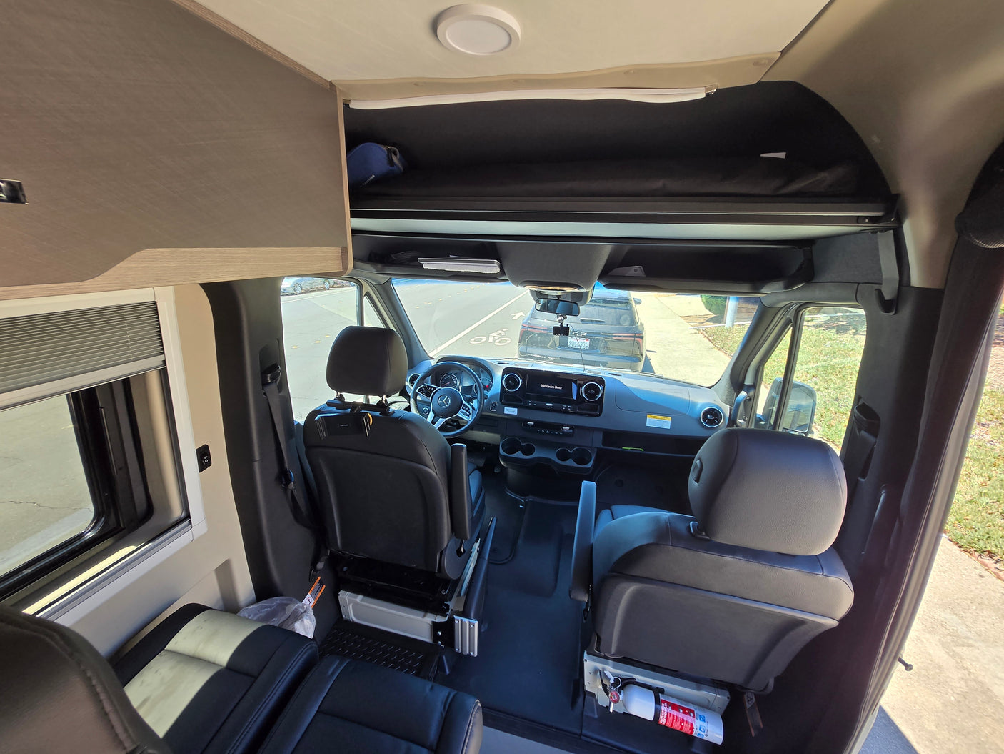 RV rental: Mercedes-Benz campervan interior showing cockpit, front seats, and overhead bunk.