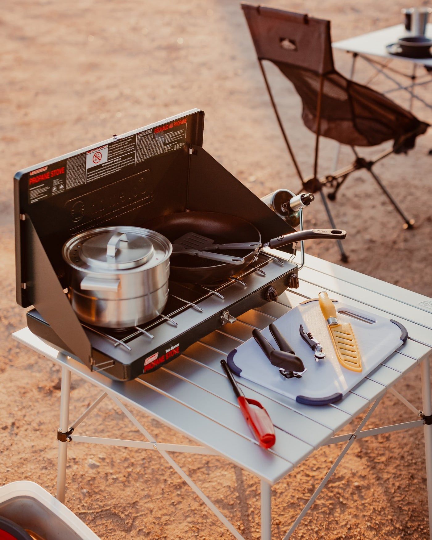 RV rental outdoor cooking setup with a Coleman propane stove, pot, pan, and cutting board on a portable table. — photo 13