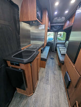 Inside this rv rental: a compact kitchen, comfortable seating, and wood-look flooring creating a cozy living space.