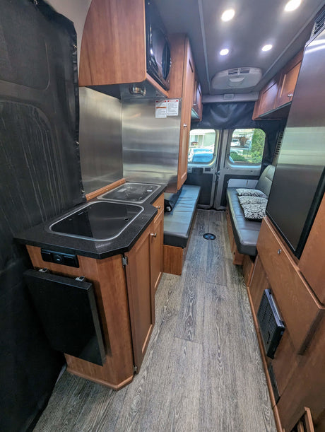 Inside this rv rental: a compact kitchen, comfortable seating, and wood-look flooring creating a cozy living space.
