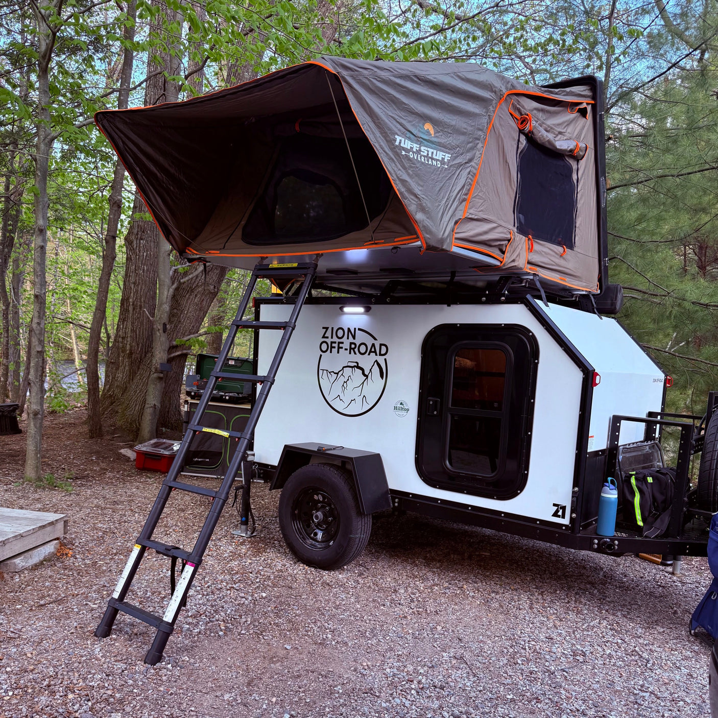 This RV rental teardrop trailer, equipped with a Tuff Stuff rooftop tent, offers an ideal setup for an overland camping adventure.