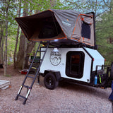 This RV rental teardrop trailer, equipped with a Tuff Stuff rooftop tent, offers an ideal setup for an overland camping adventure.