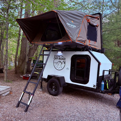 This RV rental teardrop trailer, equipped with a Tuff Stuff rooftop tent, offers an ideal setup for an overland camping adventure.