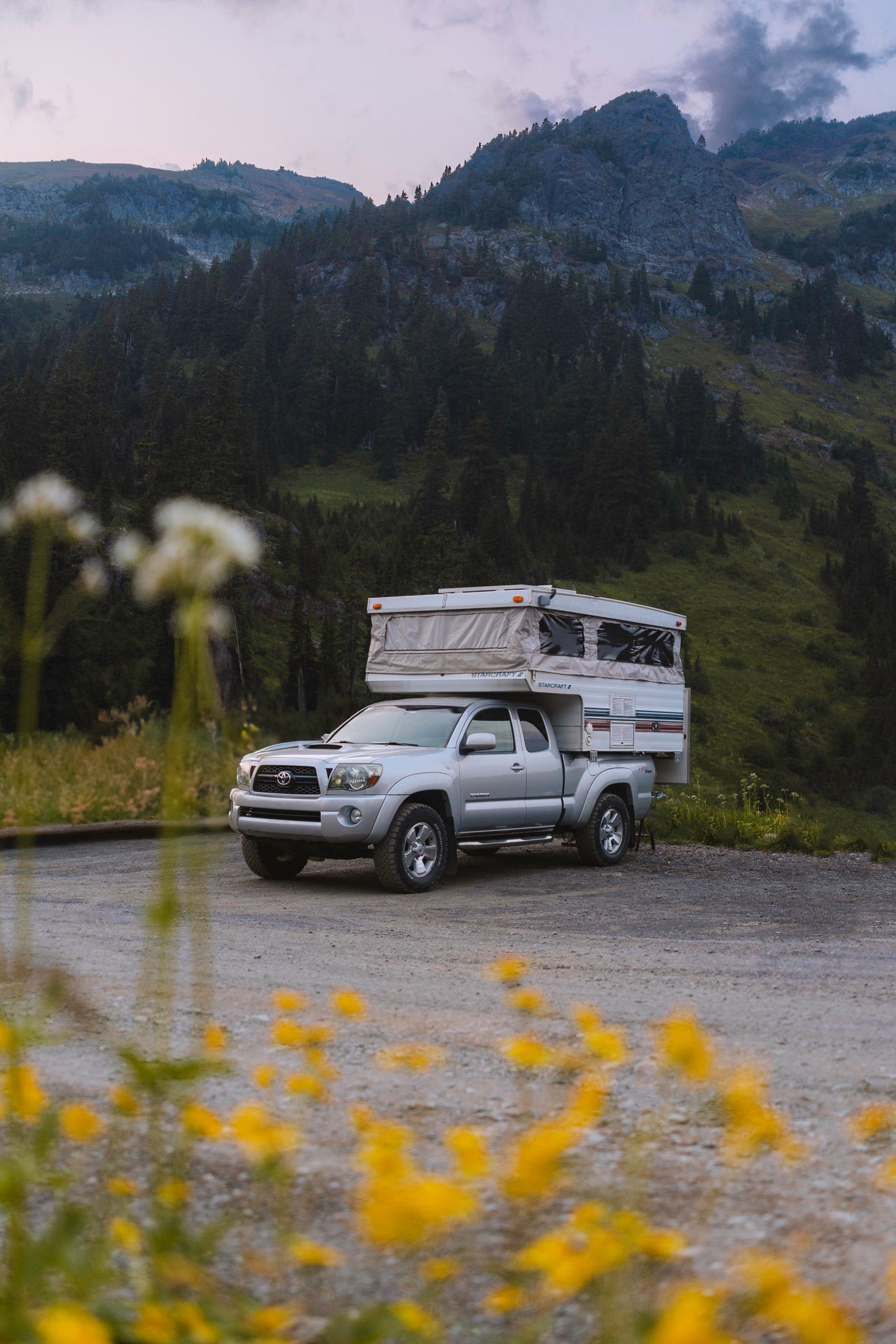 Explore with an RV rental! Silver Toyota Tacoma truck with a pop-up camper parked in a scenic mountain landscape. — photo 4