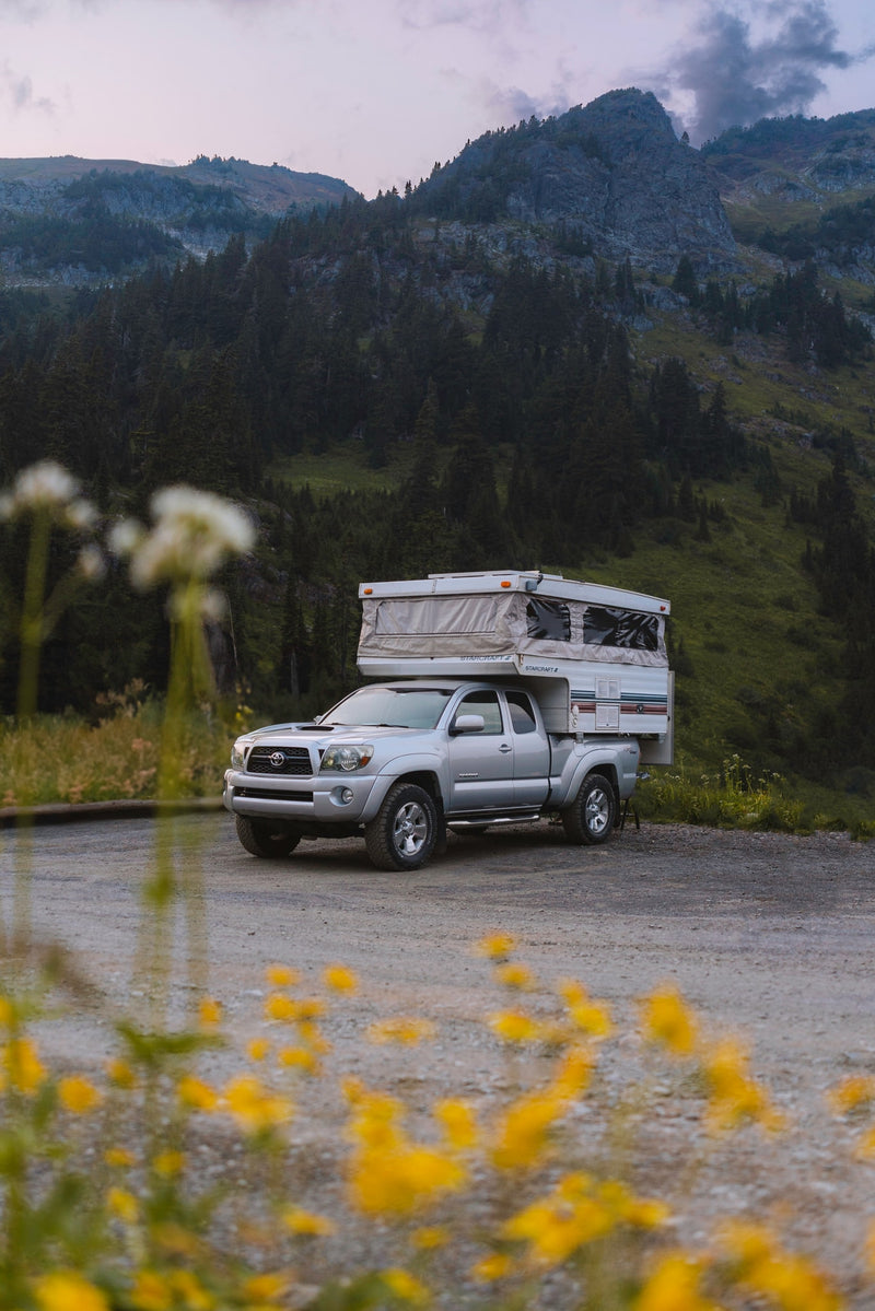 Explore with an RV rental! Silver Toyota Tacoma truck with a pop-up camper parked in a scenic mountain landscape. — photo 4