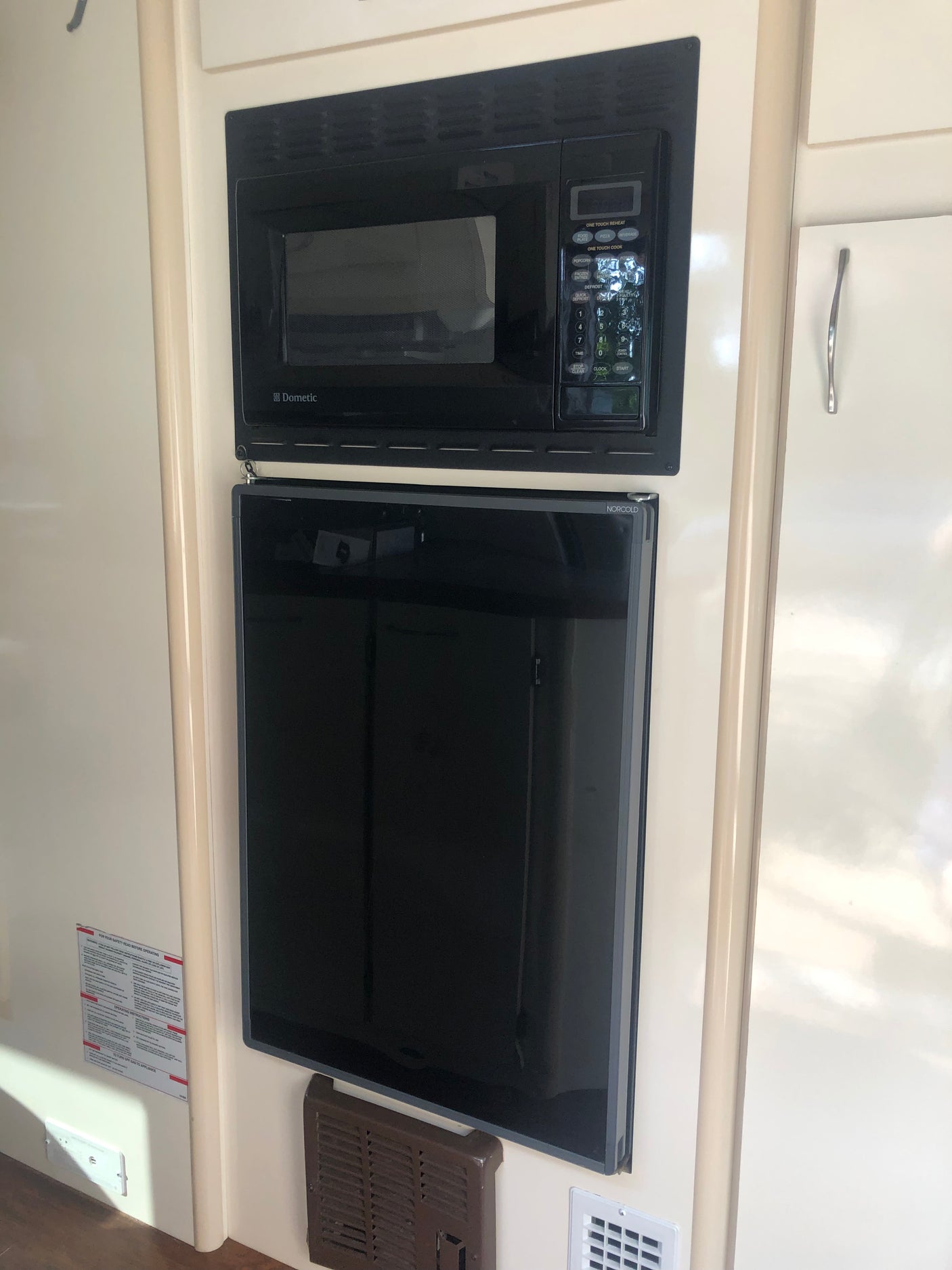 Black Dometic microwave above a Norcold refrigerator, essential appliances for your RV rental kitchen.