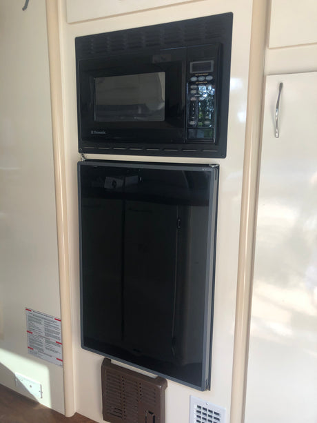Black Dometic microwave above a Norcold refrigerator, essential appliances for your RV rental kitchen.