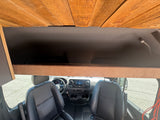 RV rental camper van's front interior, showcasing black seats, dashboard, an overhead storage compartment, and a plank wood ceiling.