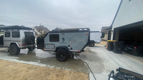 A G-Wagon tows a sleek Mission Overland RV trailer, ready for adventure. Explore RV rental options for similar trips!